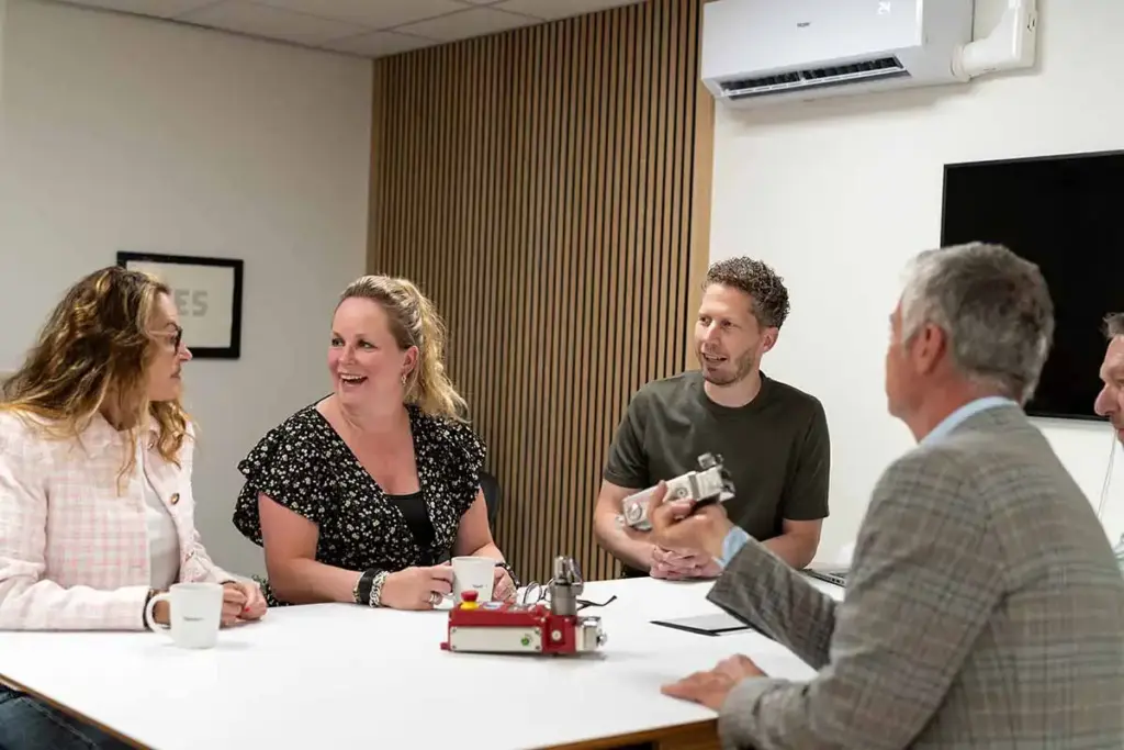 Team van Teleson in overleg samen aan tafel over sensoren en machineveiligheid en veiligheidsschakelaars.