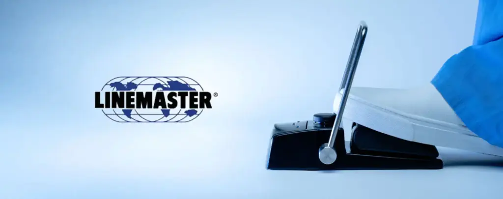 Linemaster voetschakelaar met beschermbeugel, bediend door een operator in medische kleding, naast het Linemaster-logo op de website van distributeur Teleson